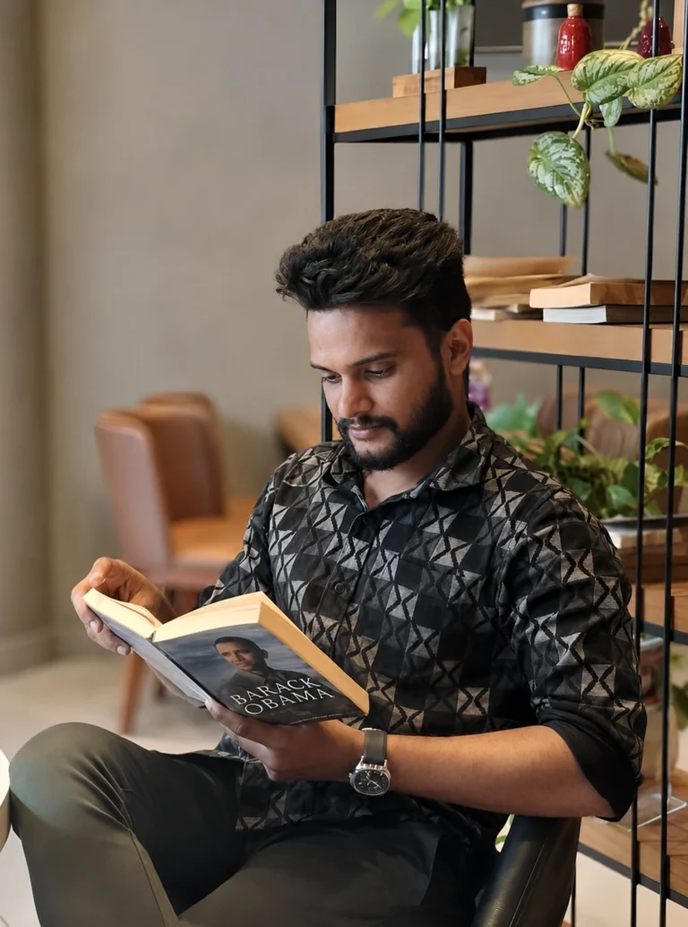 Nishad Ismail reading a book in a modern indoor setting, showcasing a professional and focused personality of an SEO Specialist in Kerala.